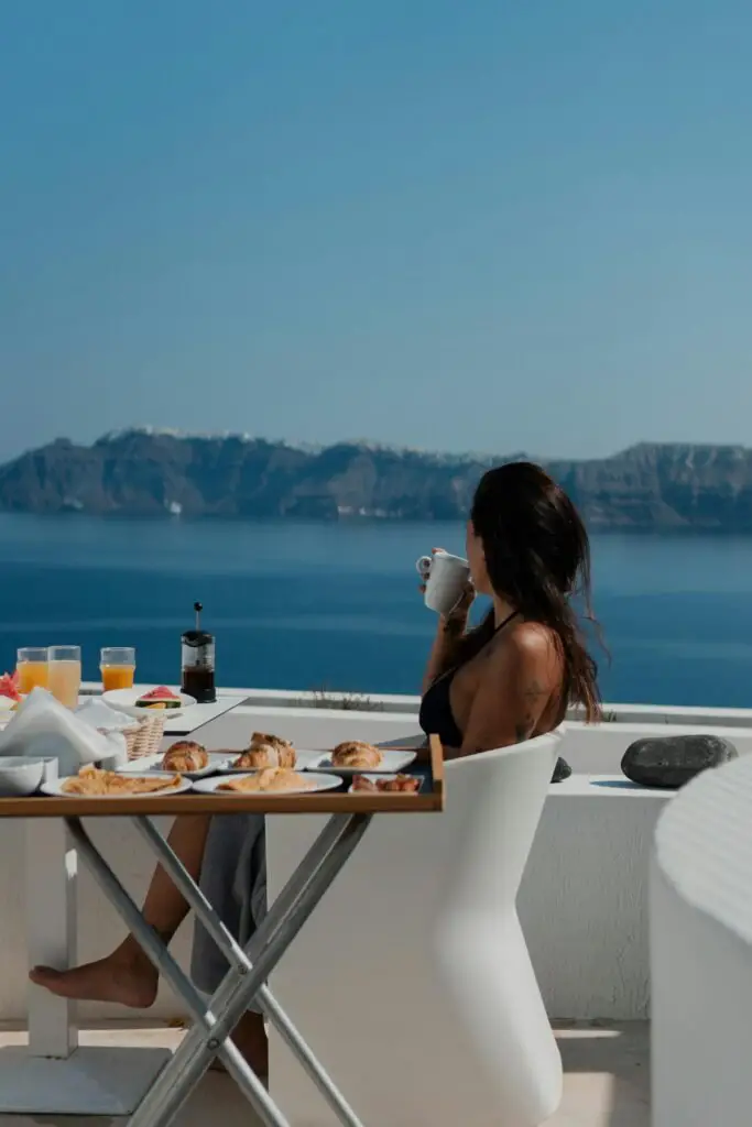 A woman sitting at a table with a view of the ocean